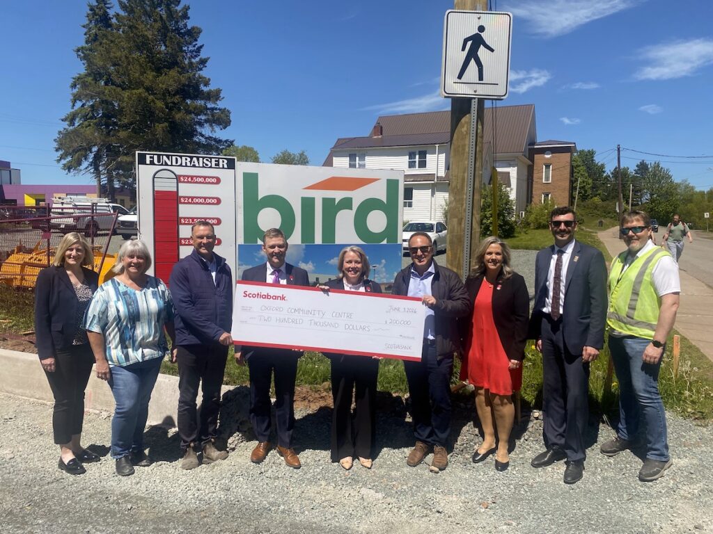 Members of the eastlink Wild Blueberry Centre board with representatives of the Bank of Nova Scotia pose in front of the fundraising thermometer at the entrance to the project site.